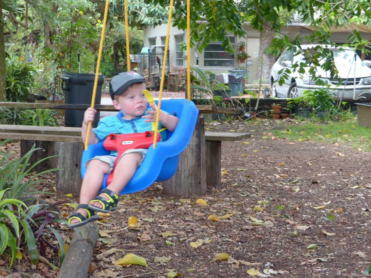 Vitus on the swing at the sanctuary — hat, sandals, and total contentment