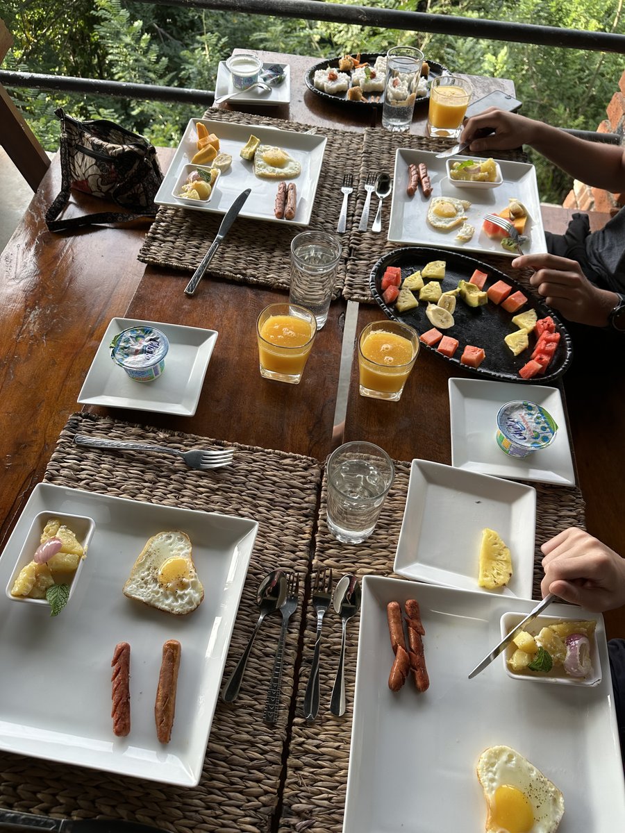 A guesthouse breakfast table laid with fruit, eggs, sausages and glasses of juice