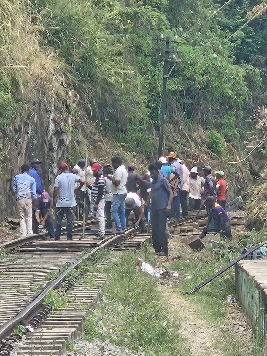 A crowd of men working on and watching a section of the railway track