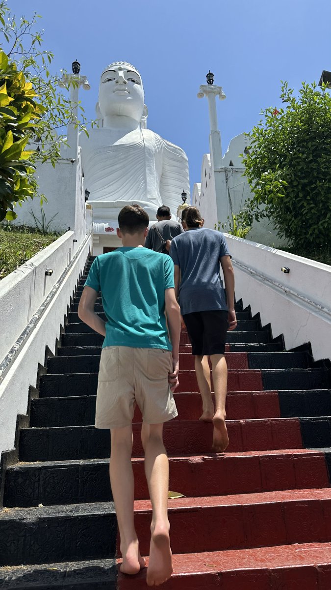Noah and Vitus climbing the steps barefoot up to the giant white Buddha