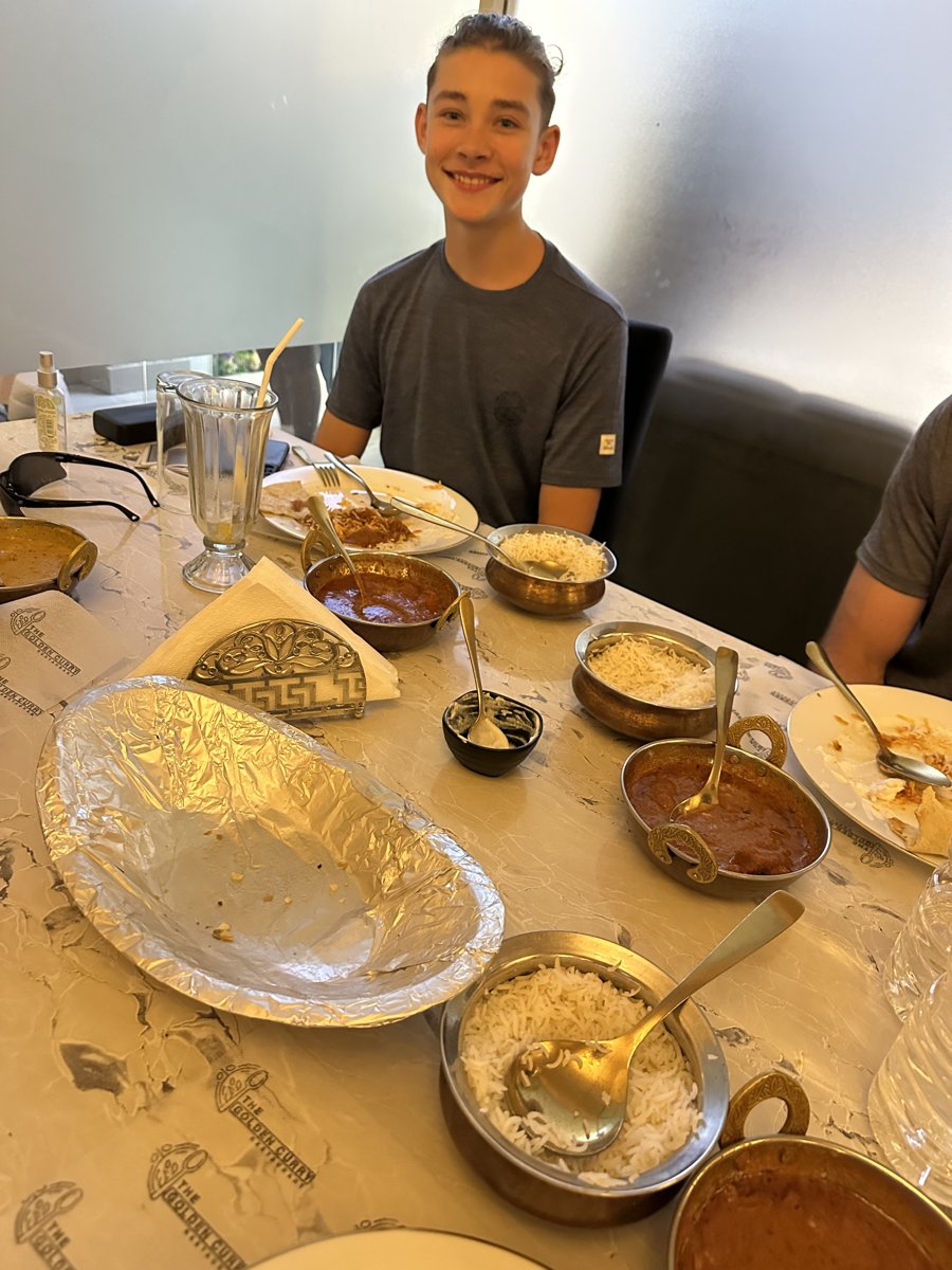 Noah at a table spread with rice, curries and a milkshake at an Indian restaurant in Kandy