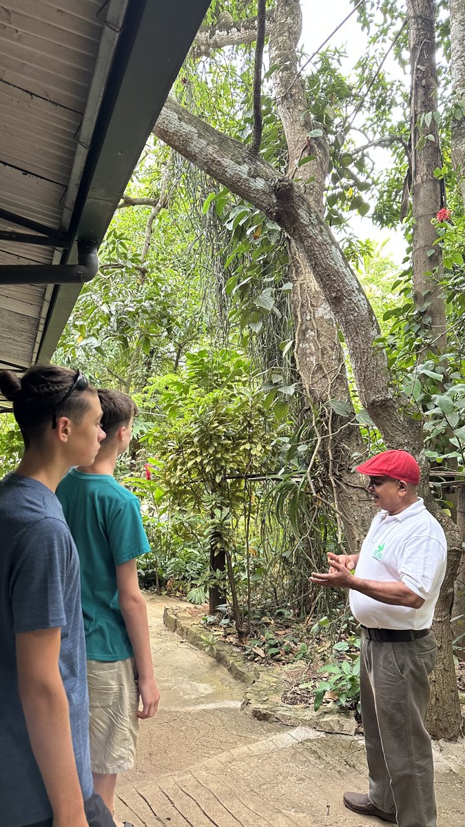 Noah and Vitus listening to a guide at a lush spice garden on the road to Kandy