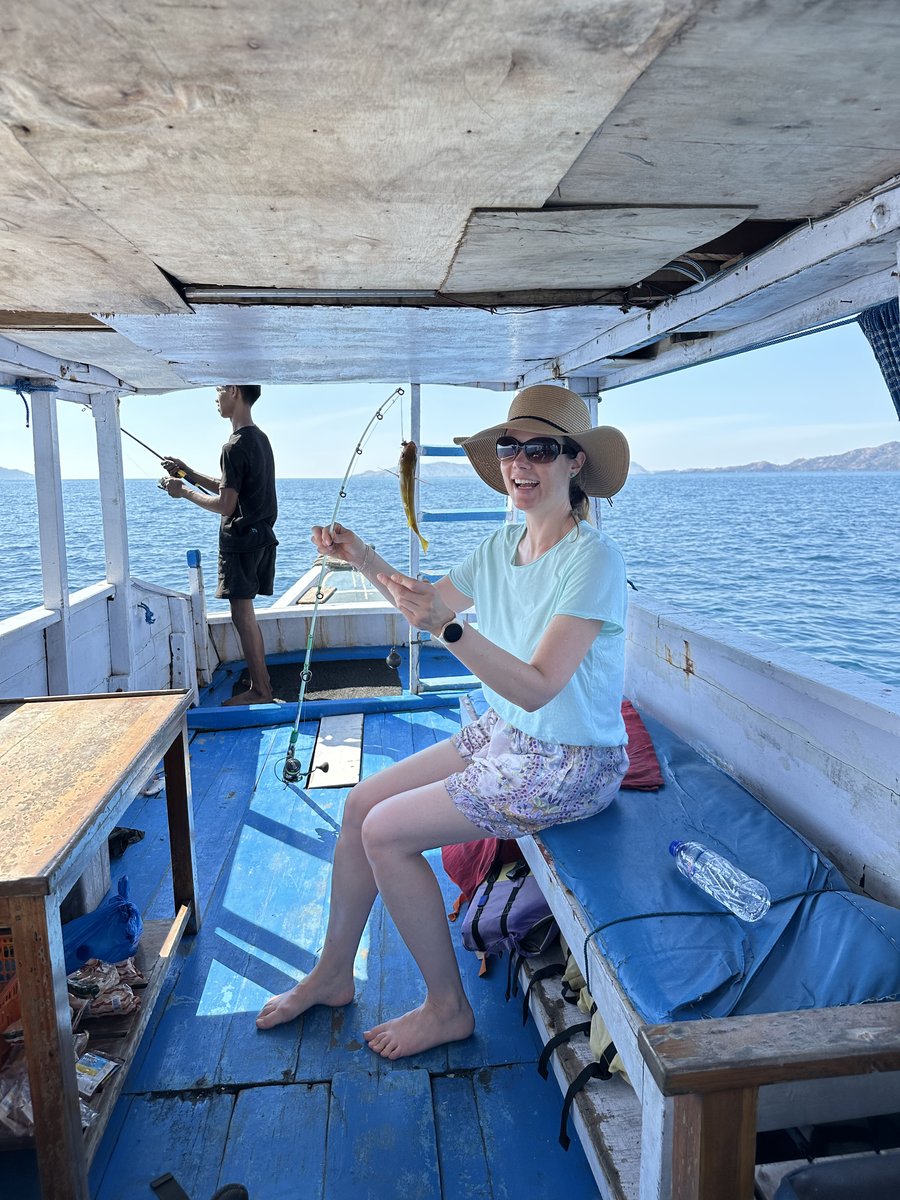 Line laughing on the fishing boat holding up her line with a small fish