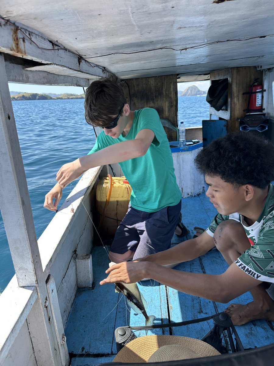 Vitus and the young boatman working a fish off the line together