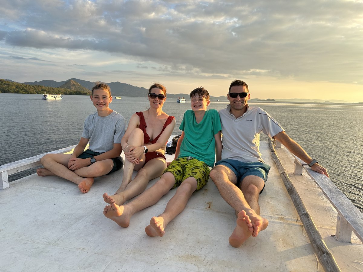 The whole family sitting on top of the boat at sunset