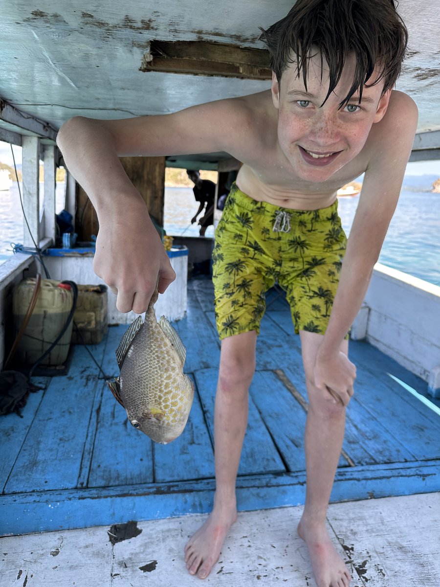 Vitus, wet from the water, proudly holding up another of his fish