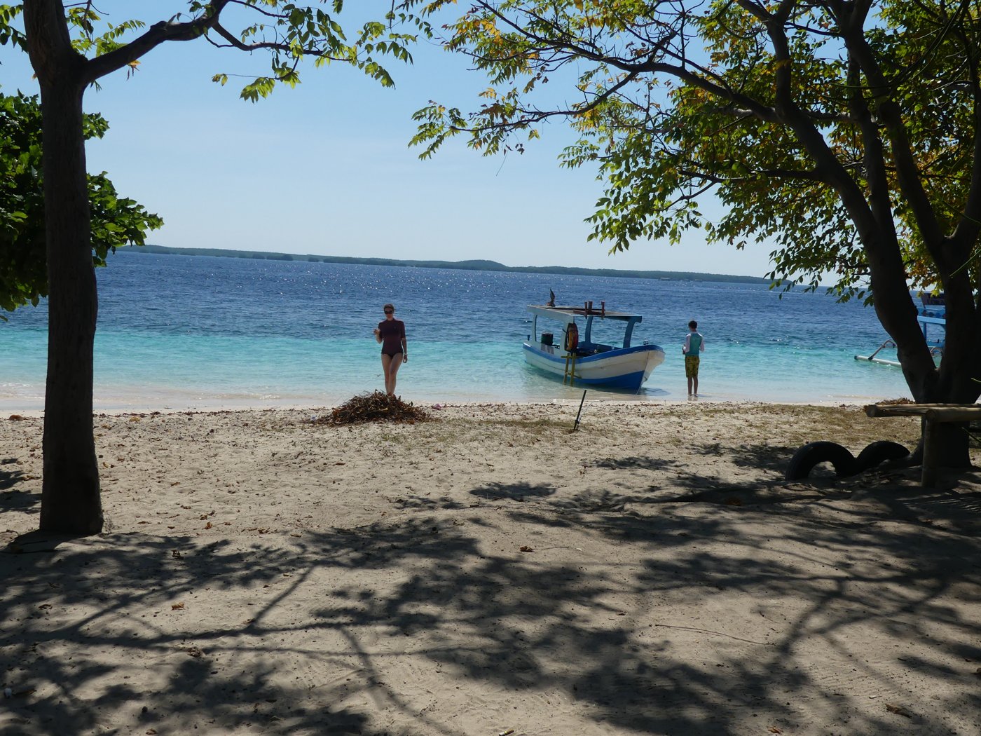 A quiet beach with the boat and mainland behind