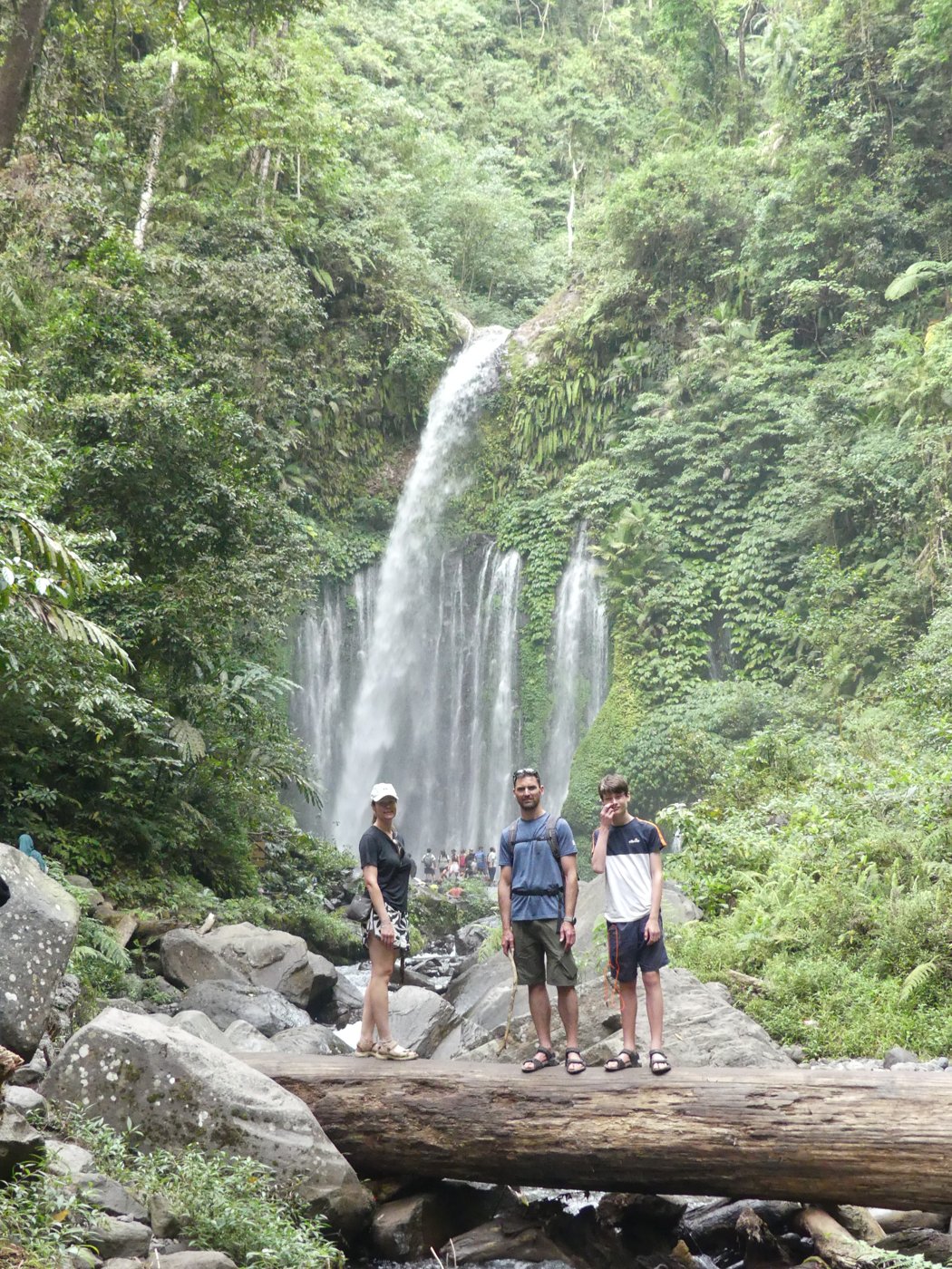 The family on the rocks at the foot of the waterfall
