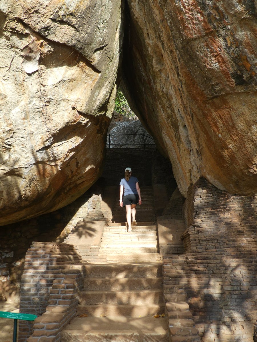 Line climbing brick steps between two enormous boulders on the Sigiriya ascent