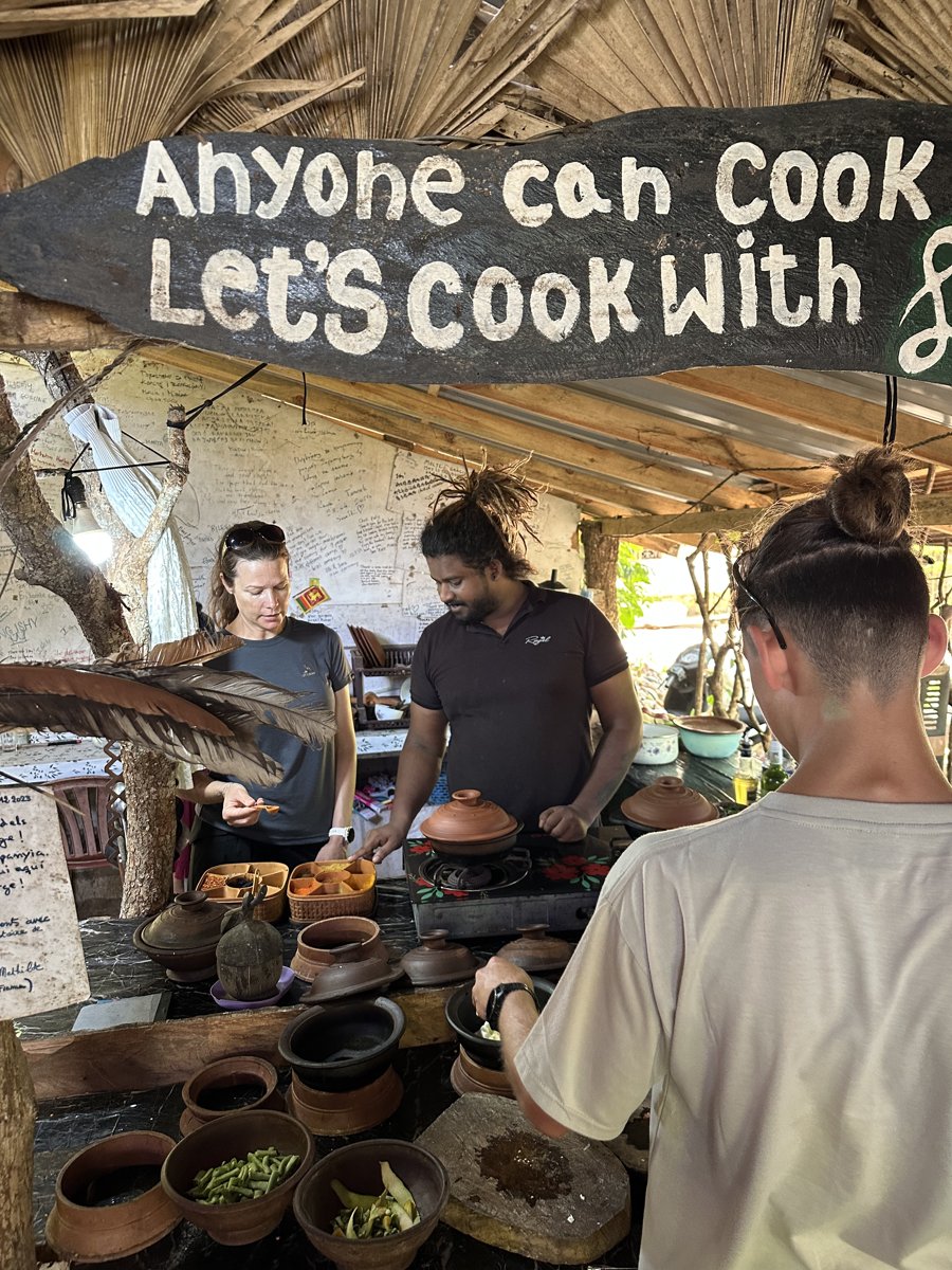 Ishy demonstrating at a clay pot under an 'Anyone can cook' sign, Line and Noah watching