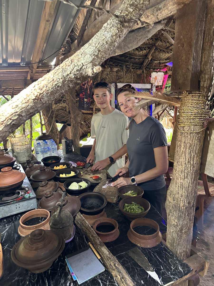 Noah and Line at the cooking class over clay pots and bowls of chopped vegetables