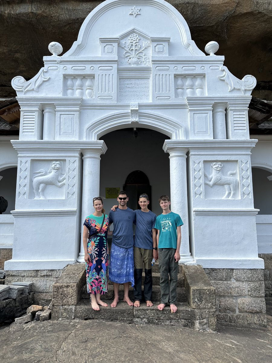 The family barefoot on the white steps of the Dambulla cave-temple entrance