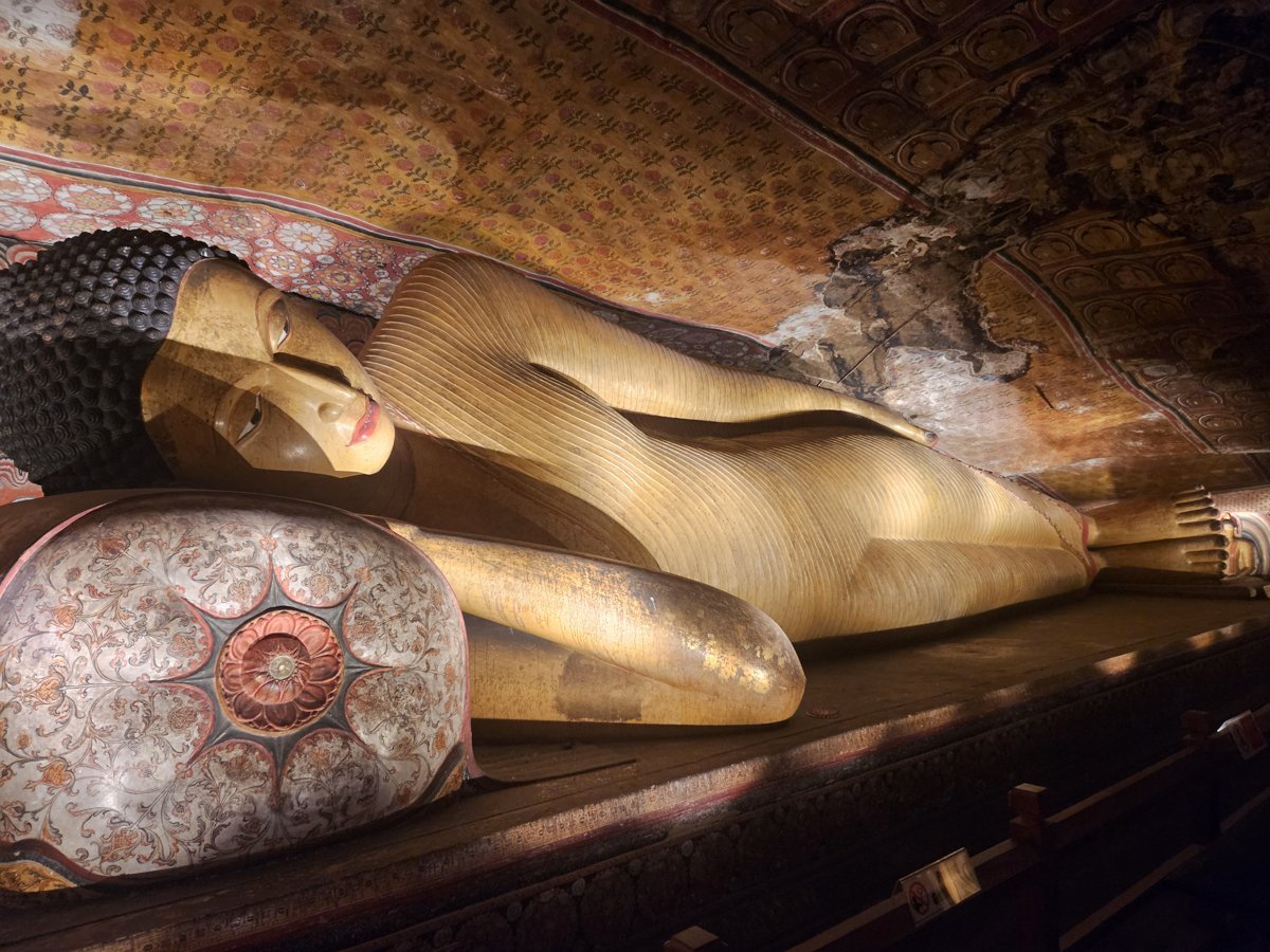 A long gilded reclining Buddha at Dambulla with an ornately painted ceiling