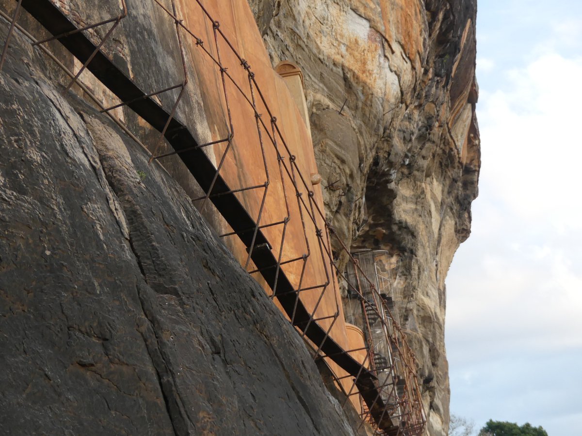 The caged walkway and orange-plastered Mirror Wall clinging to the polished rock