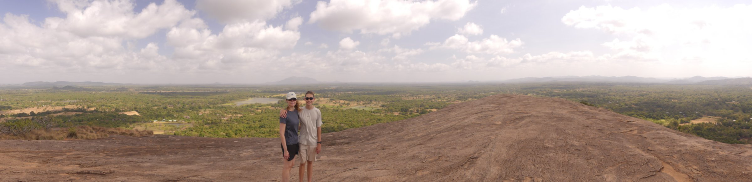Panorama from the top of Pidurangala: Line and Noah on the bare rock dome with the whole jungle plain behind