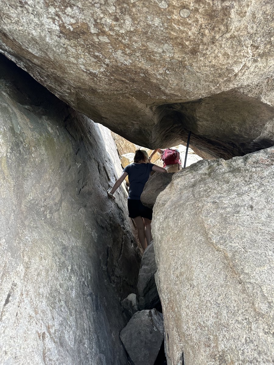 Line squeezing up through a narrow gap between huge boulders on Pidurangala