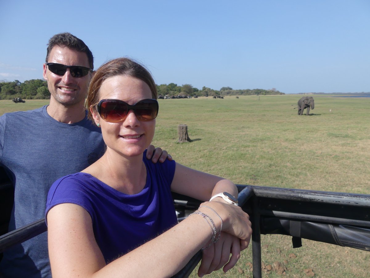 Line and Jesper in the safari jeep with elephants grazing behind them