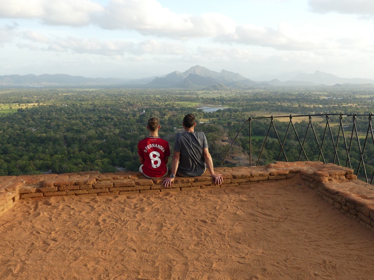 Noah and Jesper sitting on the summit wall looking out over the jungle and mountains