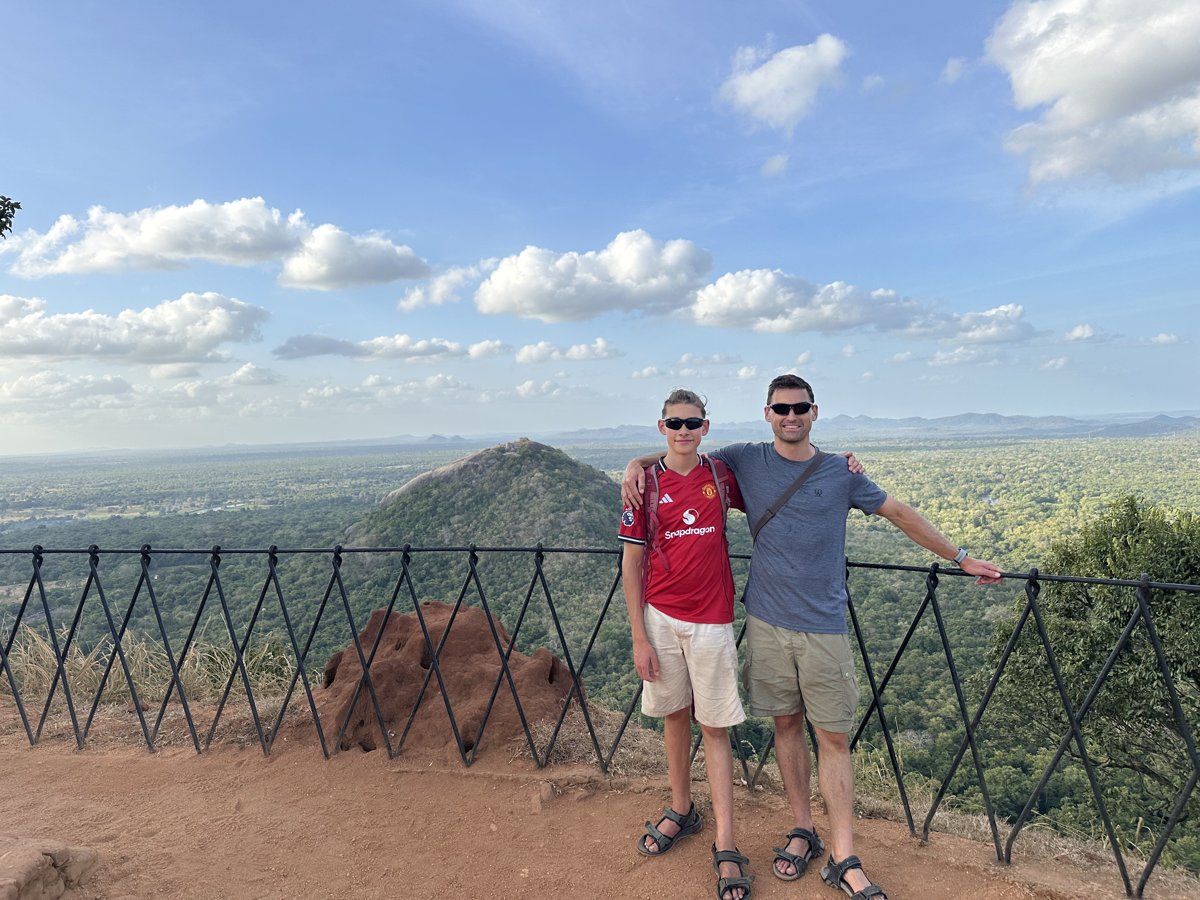 Noah and Jesper at the summit railing with jungle and hills behind