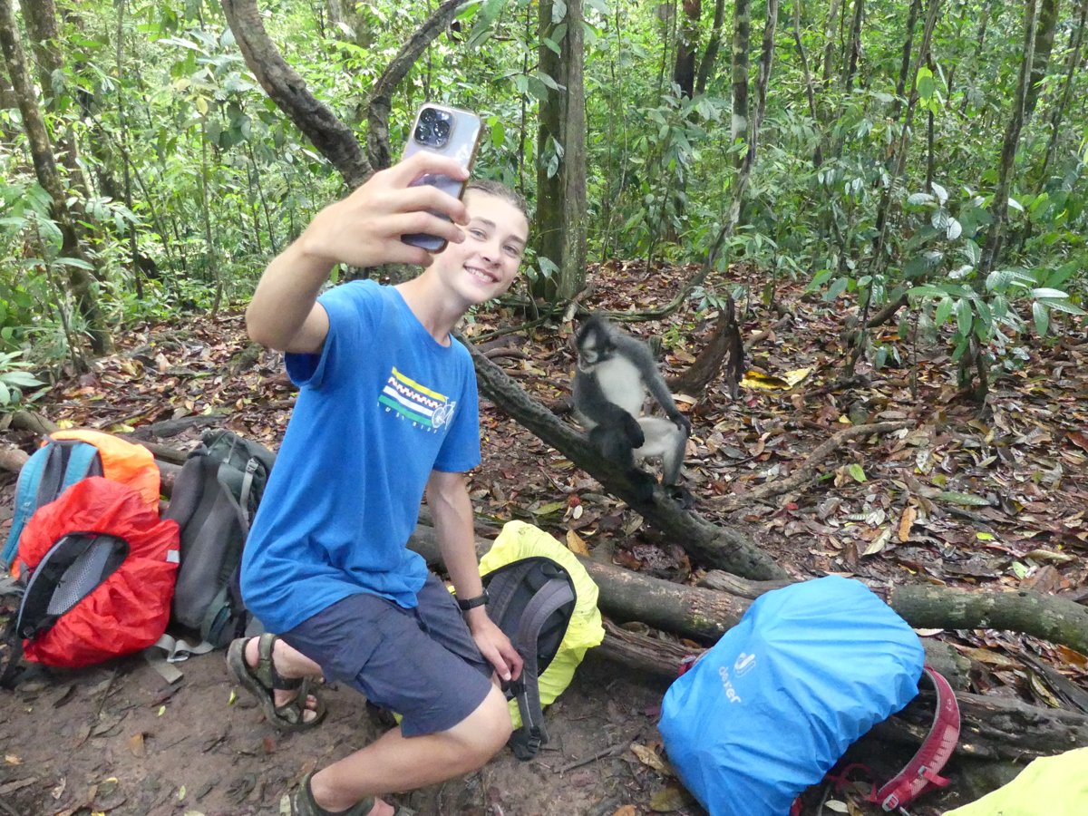 Noah taking a selfie with a Thomas leaf monkey that came right up onto the log beside the backpacks