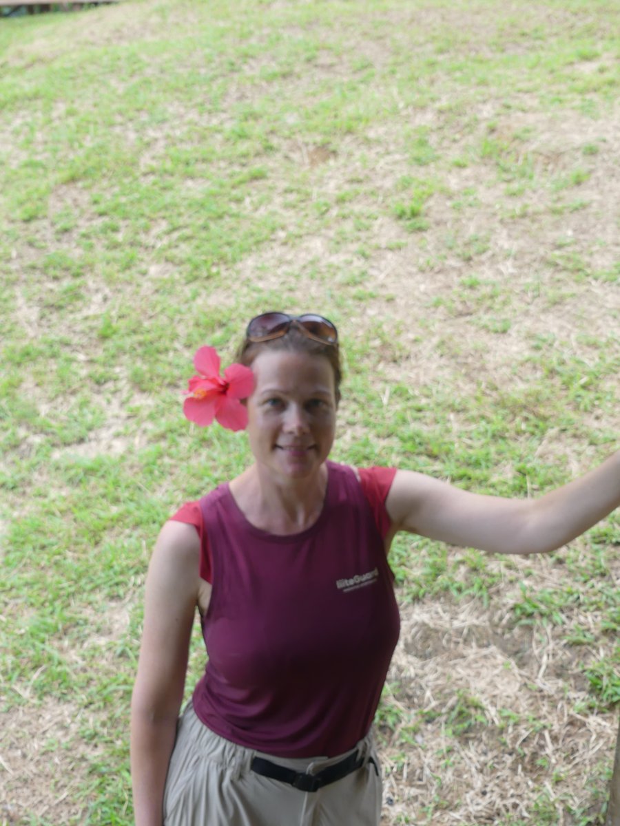 Line in the grassy camp clearing with a hibiscus flower in her hair